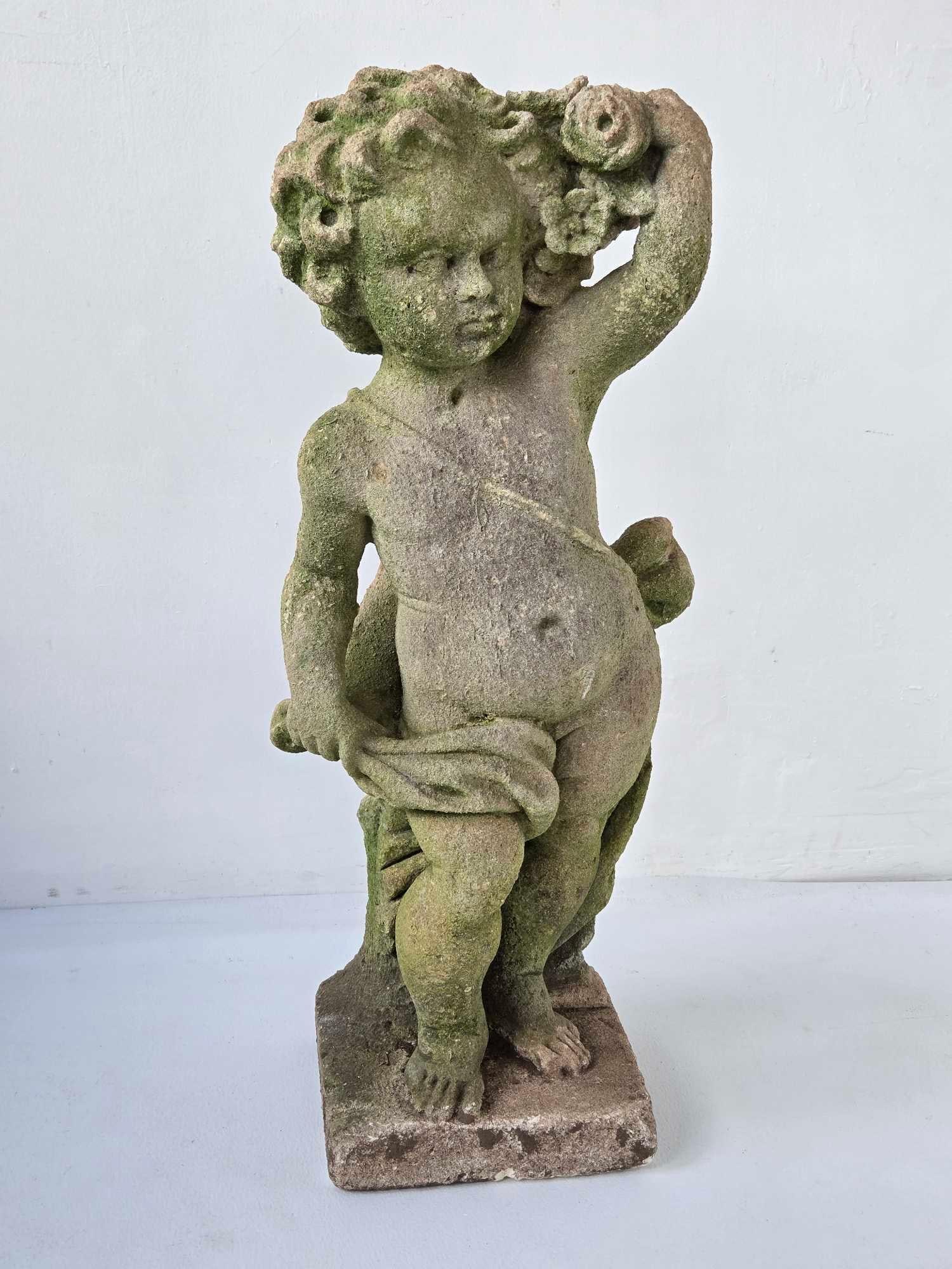 VINTAGE CAST STONE PUTTO GARDEN STATUE: A vintage cast stone garden figure of a putto holding a shell aloft, the surface naturally weathered with moss and lichen, on an integral square plinth Approximate Dimensions: 28" H x 11" W x 