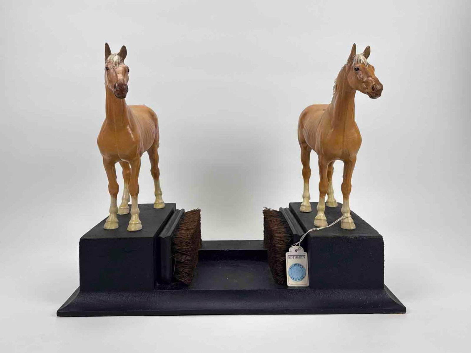 AMERICAN CAST IRON AND PAINTED DOUBLE HORSE BOOT SCRAPER: A cast iron boot scraper flanked by a pair of polychrome painted standing horses, mounted on a black painted plinth base Approximate Dimensions: 14.5" H x 19" W x 12" D Artist or Maker: Un