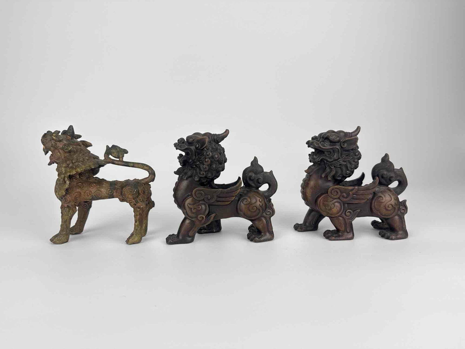 SET OF VINTAGE BRONZE FENG SHUI PIXIU GUARDIAN FIGURES: A set of small cast bronze Feng Shui guardian beasts of Pixiu or Qilin form, each with a scrolled mane, horns and clawed feet, in a dark patina Approximate Dimensions: Tallest: 5" H x 2.5" W x