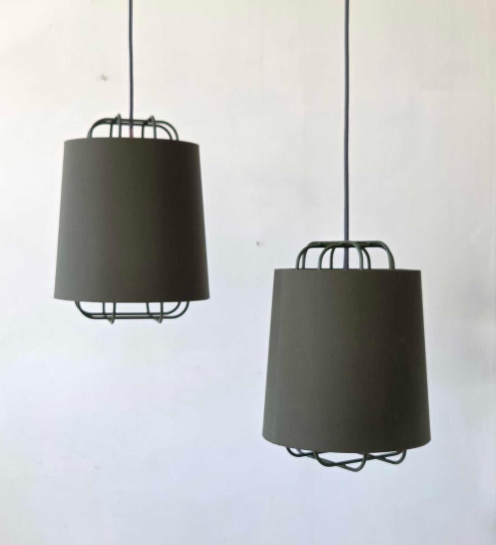 PAIR OF NUD OLIVE GREEN CAGED PENDANT LIGHTS WITH LINEN DRUM SHADES: pair of powder coated wire cage pendant lights with olive green linen drum shades and grey braided textile cords Approximate Dimensions Fixture Only: 15.5"H x 11.25"Dia Artist or Maker: NUD Pr