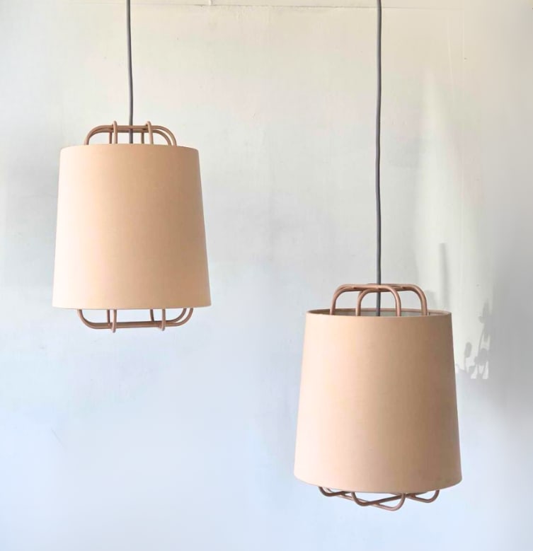 PAIR OF NUD BLUSH PINK CAGED PENDANT LIGHTS WITH LINEN DRUM SHADES: pair of powder coated wire cage pendant lights with blush pink linen drum shades and grey braided textile cords Approximate Dimensions Fixture Only: 15.5"H x 11.25"Dia Artist or Maker: NUD Pro