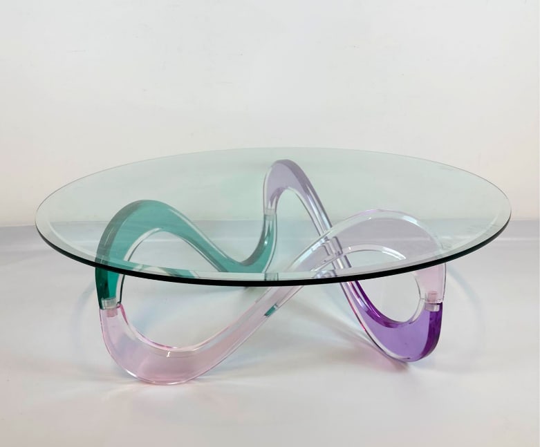 SHLOMI HAZIZA "INFINITY" LUCITE AND GLASS COFFEE TABLE: Shlomi Haziza "Infinity" coffee table, featuring a sculptural ribbon-form multicolor lucite base supporting a round beveled glass top, circa 1990s. Approximate Dimensions: 16.25"H x 42"