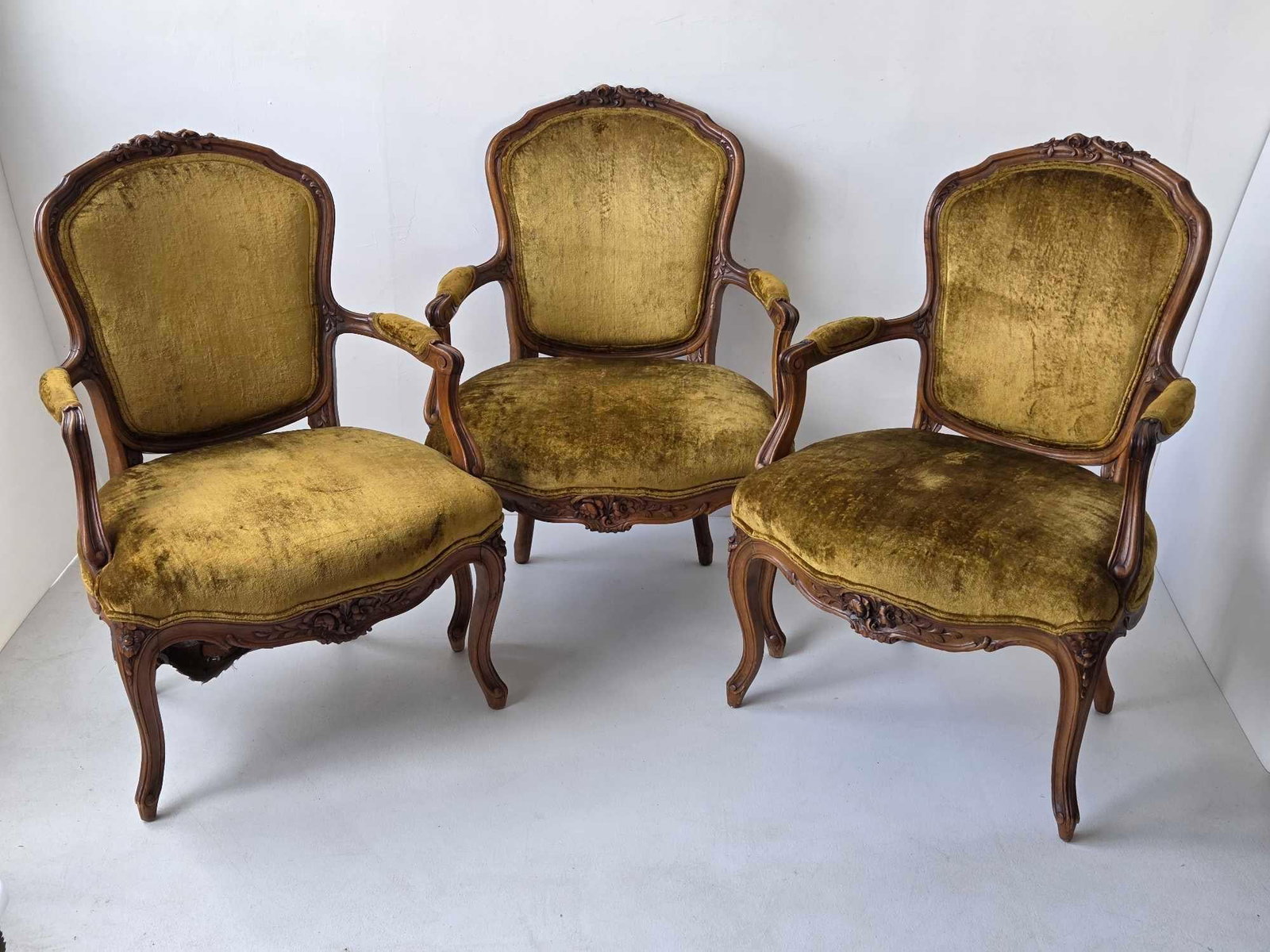 SET OF THREE LOUIS XV STYLE CARVED WALNUT OLIVE/CHARTREUSE VELVET UPHOLSTERED FAUTEUILS: Set of three Louis XV style open armchairs, carved show wood frames with floral crested cartouche backs, moulded scrolled arms, carved seat rails, cabriole legs, and gold velvet upholstery with stripe