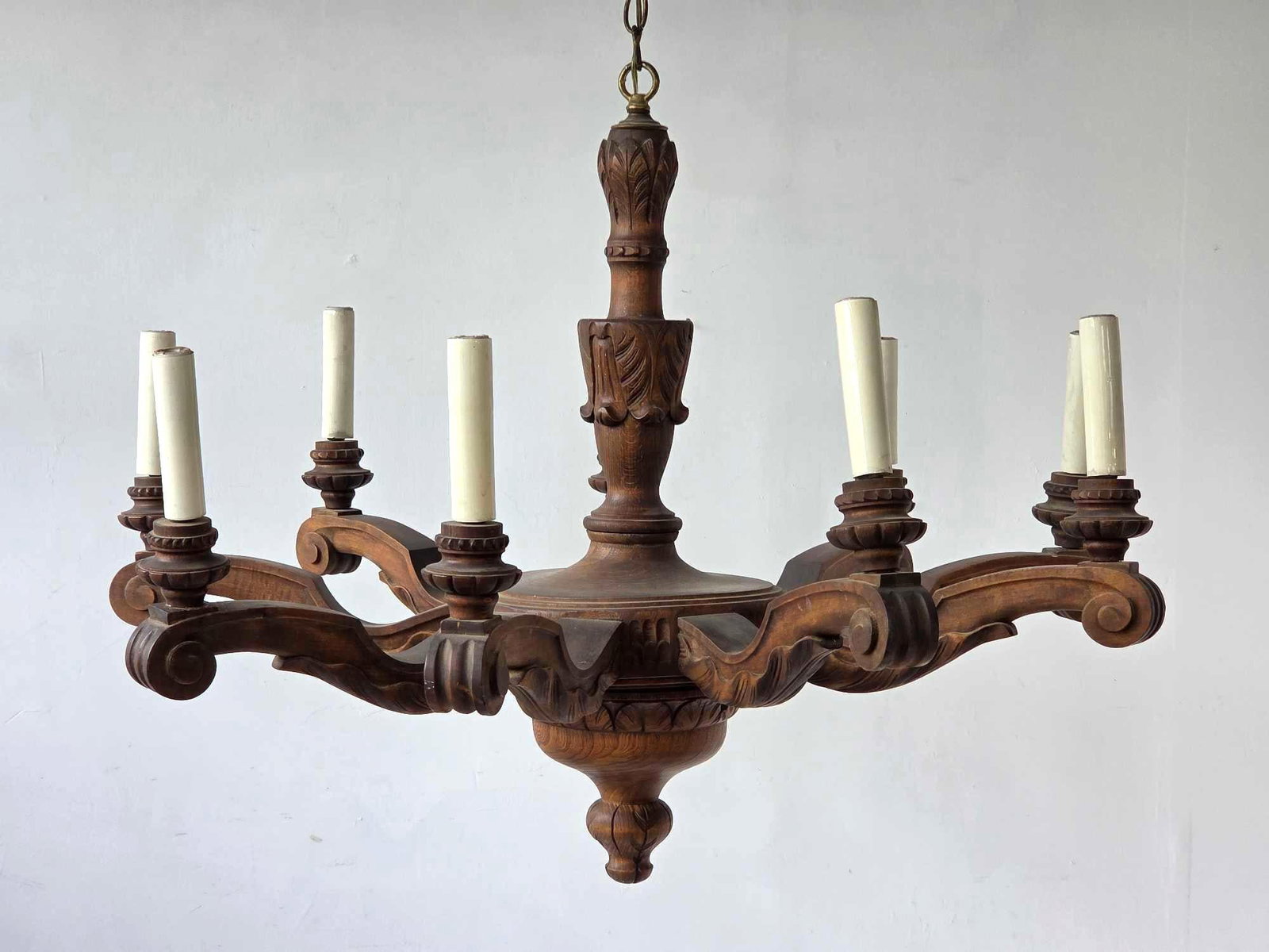 HAND CARVED WOOD NINE ARM CHANDELIER: Carved wood chandelier with scrolled acanthus arms issuing from a turned baluster standard over an urn form drop, with carved bobeches and candle sleeves, suspended on a chain Approximate Dimensions: 
