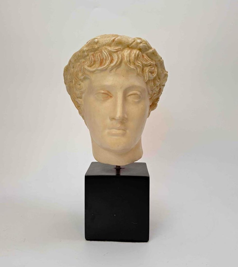 CLASSICAL STYLE HEAD SCULPTURE OF A YOUTH ON BLACK PLINTH: Classical style head of a youth, cream toned with a lightly weathered surface, mounted on a square black plinth Approximate Dimensions: 11.5" H x 6" W Artist or Maker: Metropolitan Museum of Art