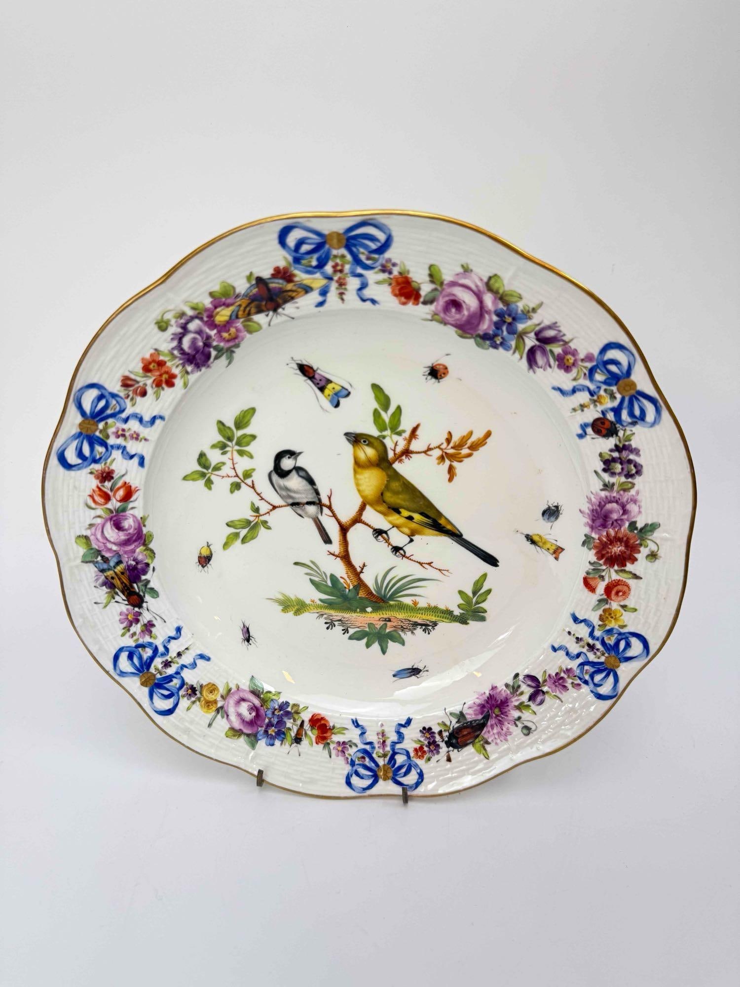 MEISSEN HAND PAINTED PORCELAIN CABINET PLATE WITH BIRD AND FLOWERS: Porcelain cabinet plate painted at the center with a yellow bird perched on a branch among scattered insects, the shaped and gilt scalloped rim with a border of blue ribbon bows and polychrome floral 