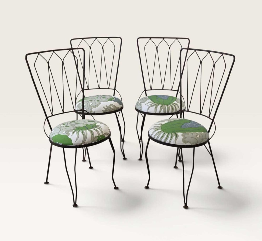 SET OF FOUR VINTAGE WROUGHT IRON BISTRO CHAIRS: Set of four wrought iron chairs with tall fan shaped backs of radiating rods, with circular upholstered seats in a green and cream leaf print, raised on splayed rod legs Approximate Dimensions: 36.5&#