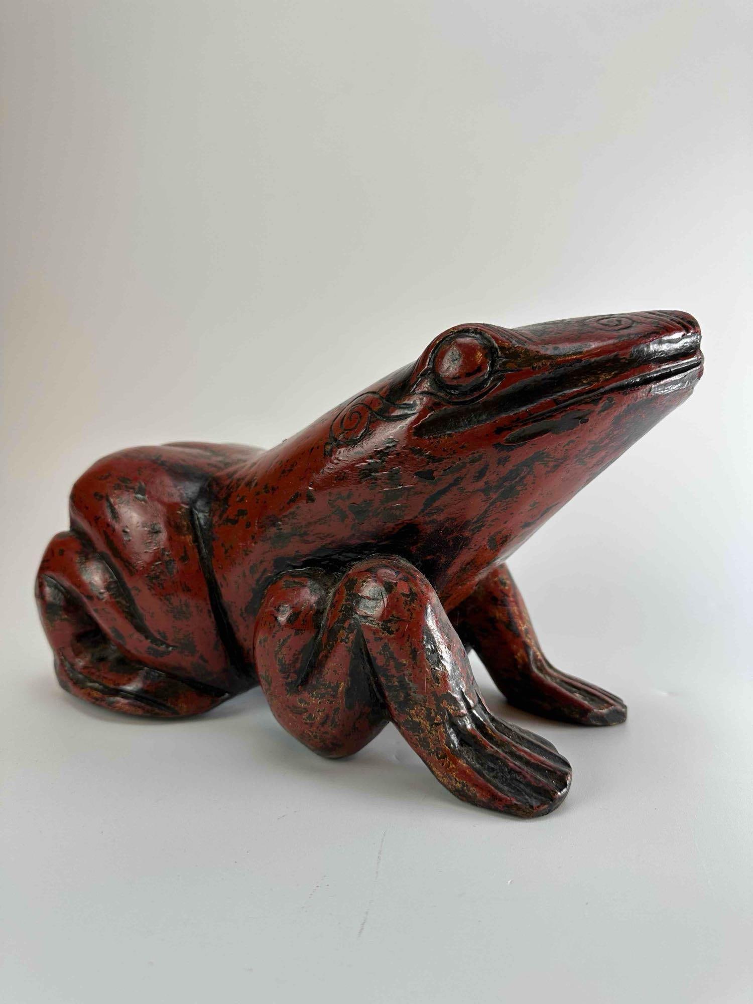 VINTAGE HAND CARVED AND PAINTED WOOD FROG: Hand carved wood frog in a crouching pose with carved eyes and webbed feet, finished in a mottled russet red stain Approximate Dimensions: 13" x 6" x 7" Artist or Maker: Unknown Provenance: From a