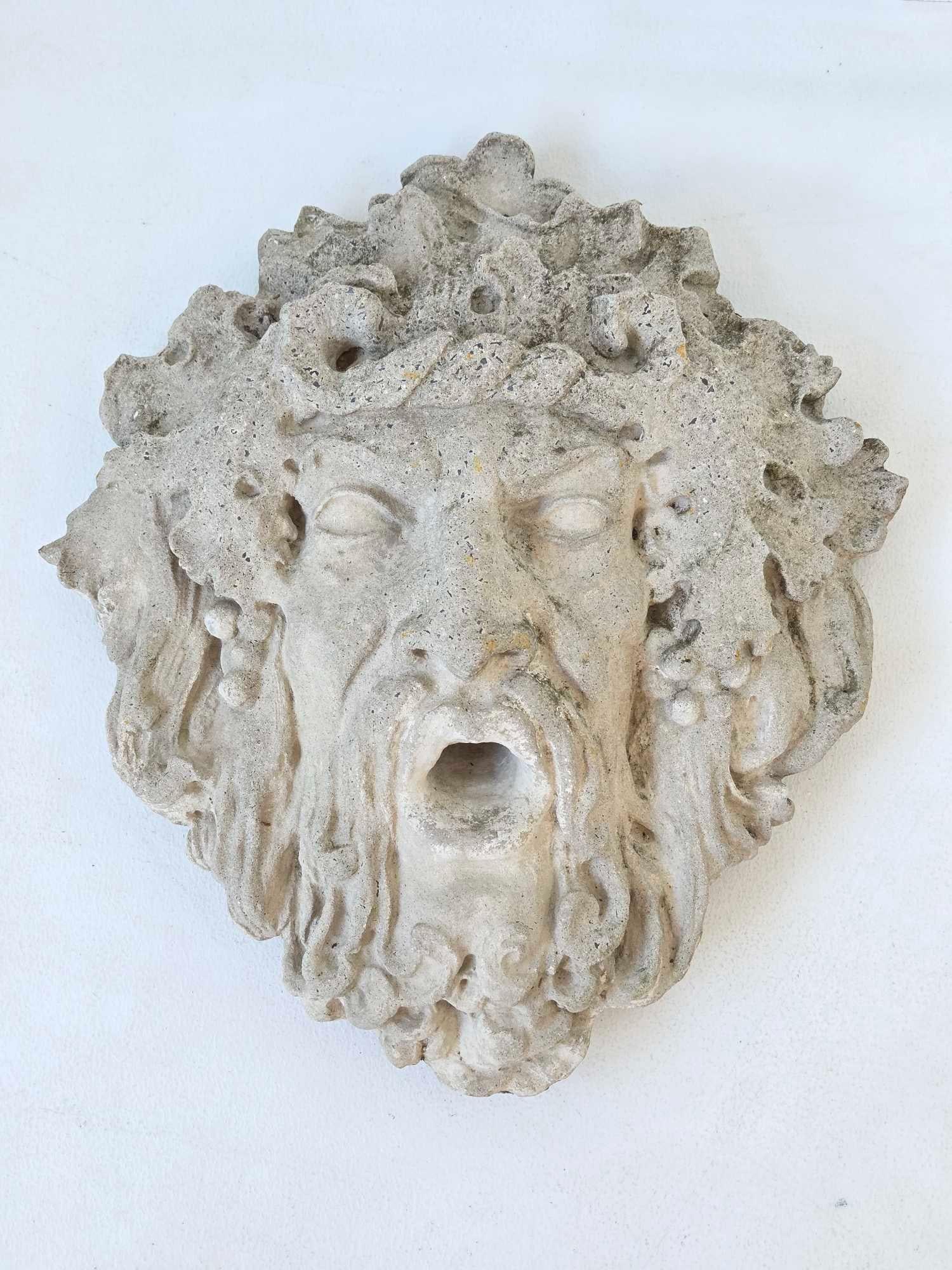 IMPRESSIVE LARGE CAST STONE BACCHUS MASK WALL FOUNTAIN SPOUT: Wall mounted fountain mask cast as the bearded head of Bacchus, the flowing hair and beard entwined with grapes and vine leaves, the open mouth pierced as a water spout Approximate Dimensions: 21"