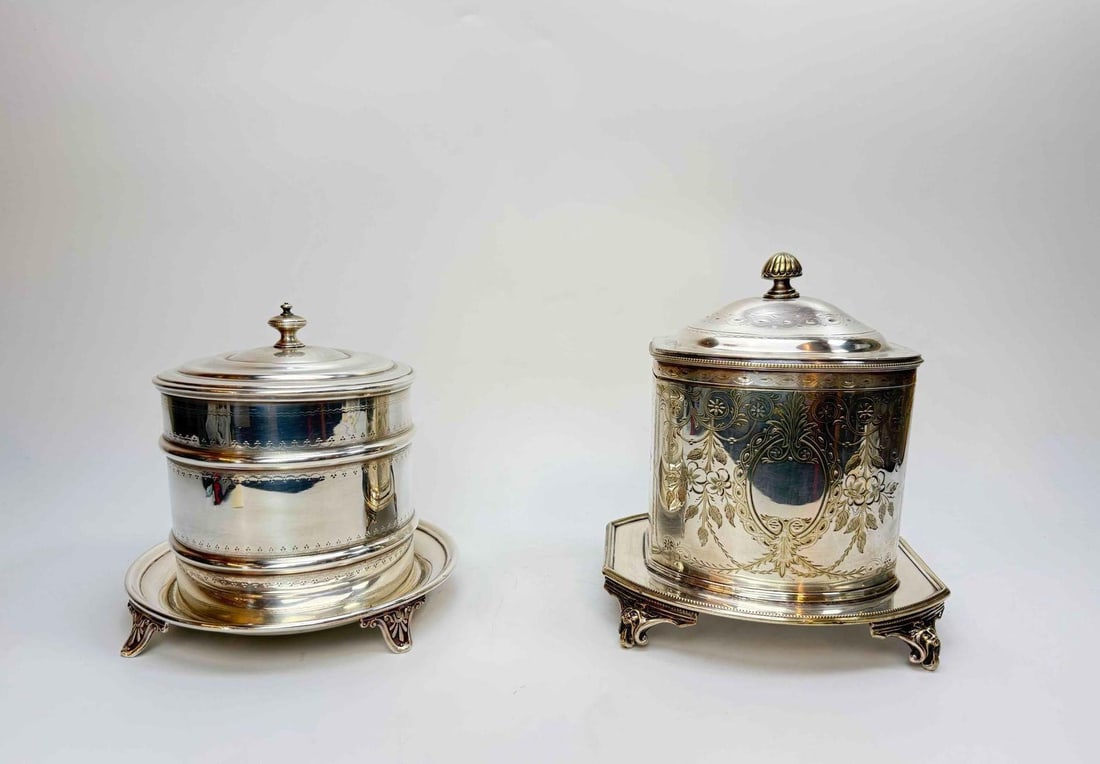 TWO VICTORIAN SILVER PLATED BISCUIT BARRELS: Two Victorian silver plated biscuit barrels, one of drum form with a stepped cover and reeded band on a circular footed base, the other of oval section with an engraved cartouche and domed cover on a 