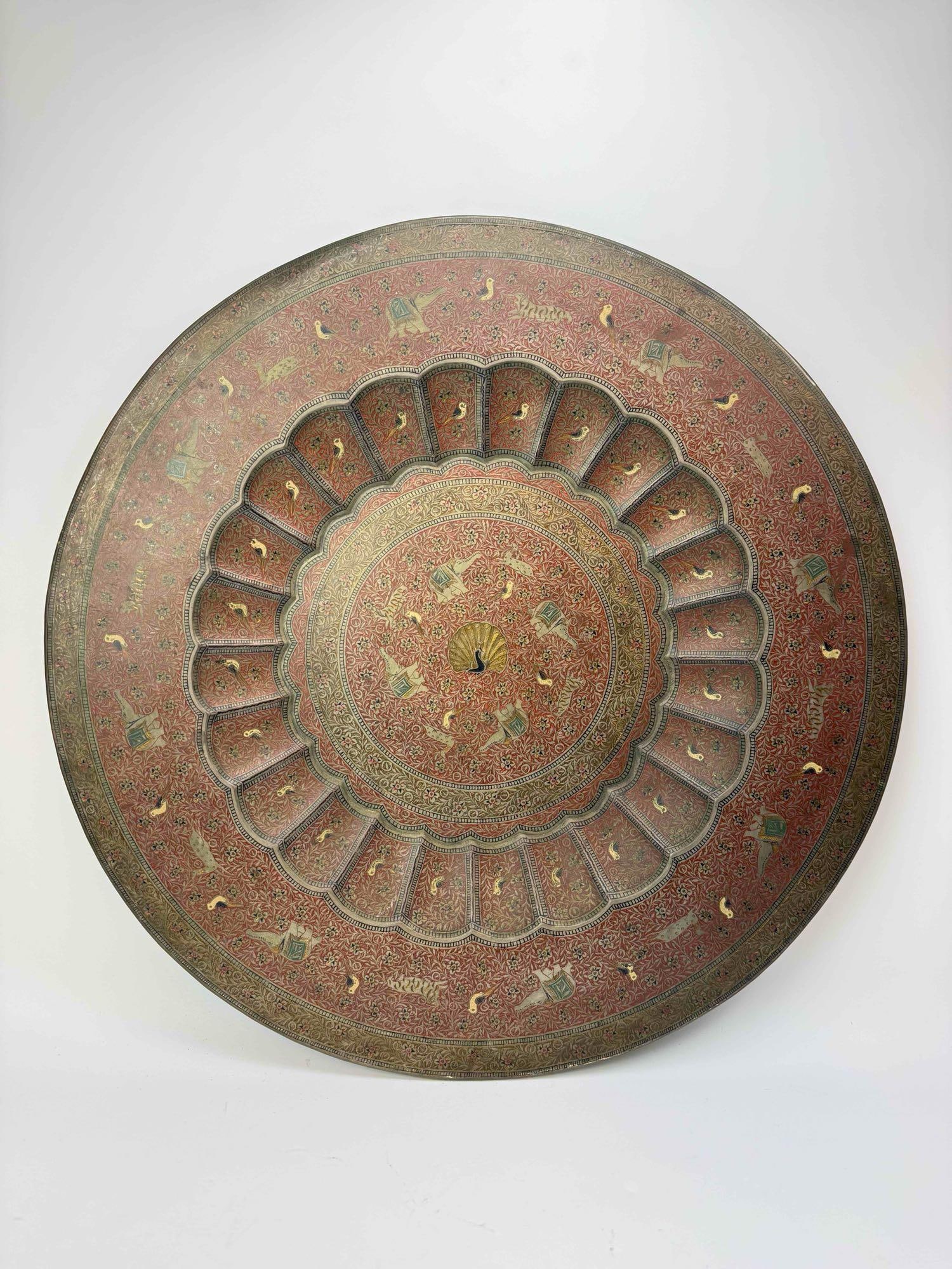 LARGE PERSIAN STYLE ENGRAVED BRASS CHARGER: A large, deeply patinated engraved brass charger with a radiating cartouche and petal border around a domed center, the surface worn to a warm red-brown Approximate Dimensions: 1" H x 23" Dia.