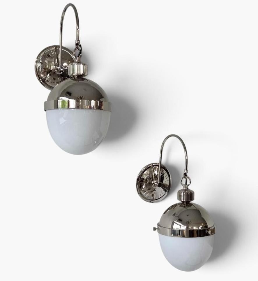 PAIR OF POLISHED NICKEL AND MILK GLASS GLOBE WALL SCONCES RETAILS FOR $1200: Pair of wall sconces in polished nickel, each with a swan neck arm rising from a round backplate to carry a globe with a polished metal upper hemisphere and a white milk glass lower half Approximate D