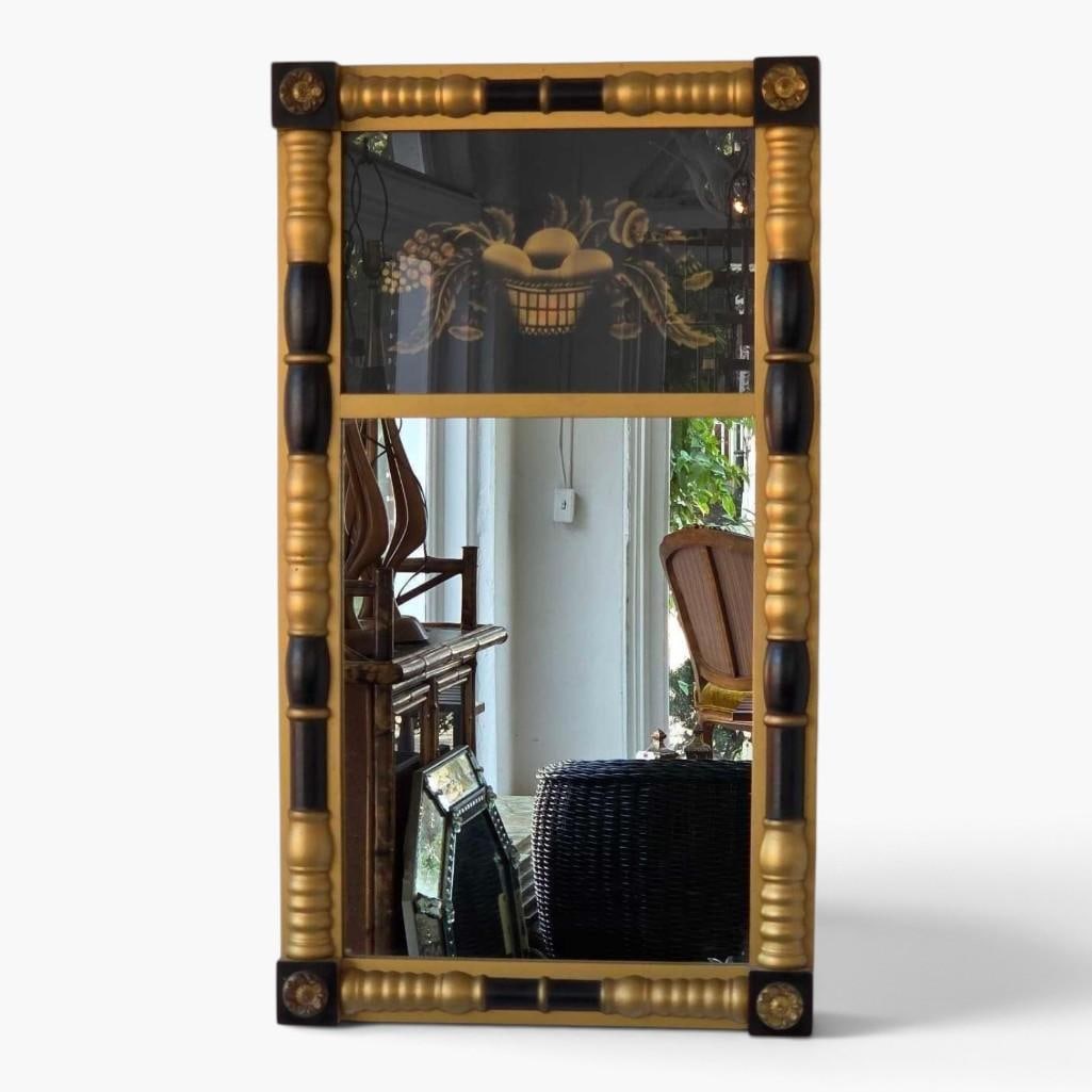 HITCHCOCK FEDERAL STYLE EGLOMISE TABERNACLE MIRROR IN BLACK AND GILT: Federal style tabernacle mirror, the black and gilt frame with half turned split columns and rosette corner blocks, the upper tablet reverse painted on glass with a gilt basket of fruit on a black gro