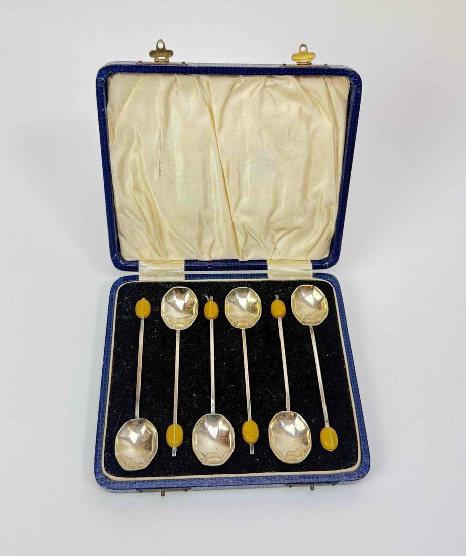CASED SET OF SIX SILVER PLATED COFFEE BEAN SPOONS WITH BAKELITE FINIALS: Cased set of six silver plated coffee spoons, each with a slender tapering stem and a turned bakelite coffee bean finial. Approximate Dimensions: 1" H X 5.75" W (case) Artist or Maker: Unknown