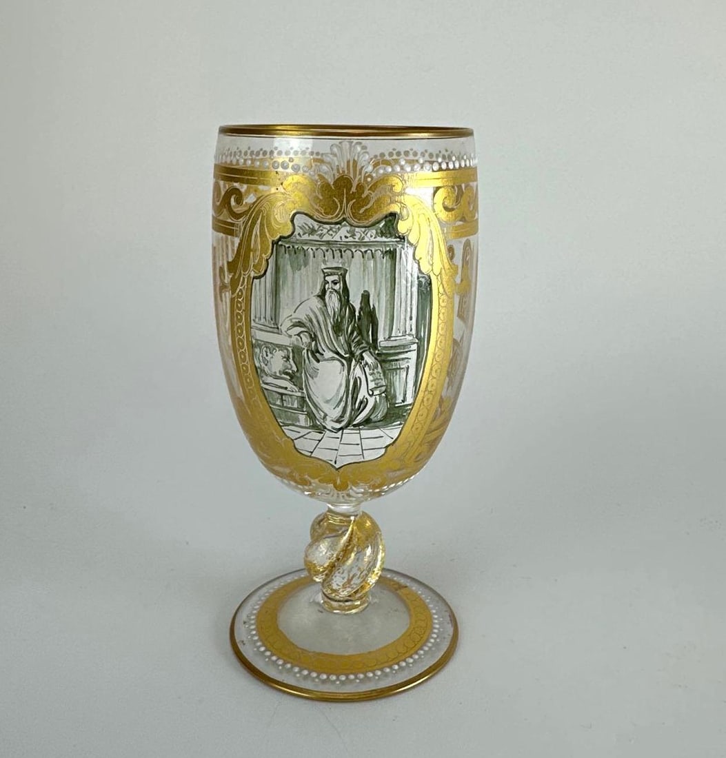 BOHEMIAN GILT DECORATED GLASS GOBLET WITH FIGURAL MEDALLION: Tall glass goblet enamelled and gilt with a figural medallion within an elaborate gilt scrolled cartouche, with gilt banding to the rim and foot, raised on a knopped clear stem Approximate Dimensions: