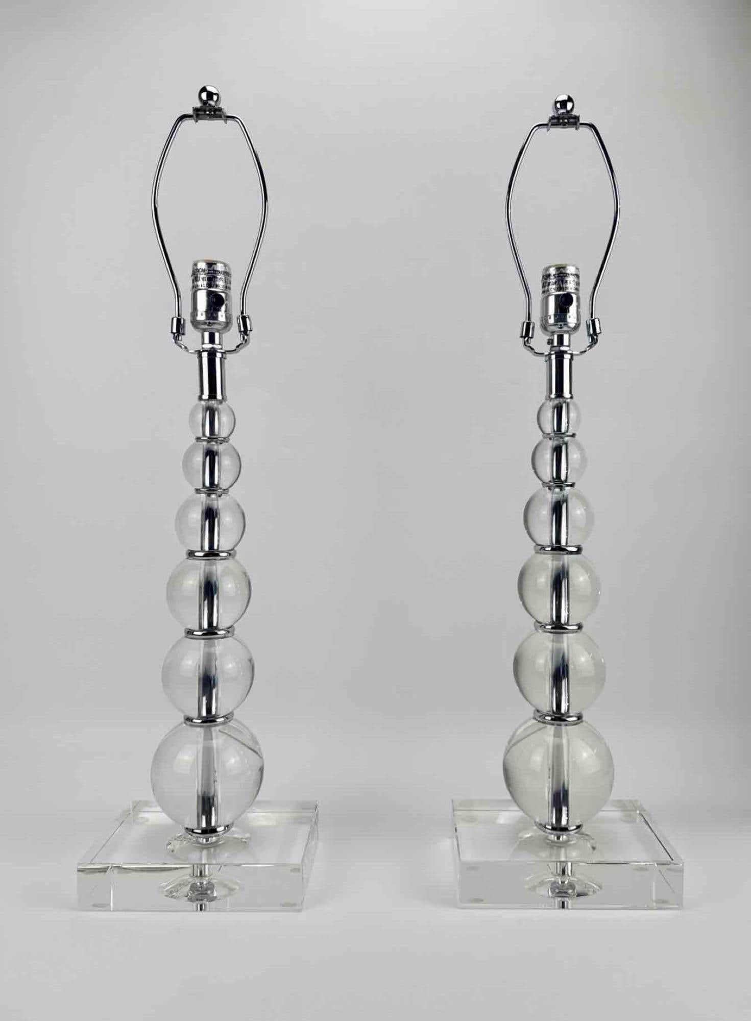 PAIR OF ACRYLIC GRADUATING STACKED ORB TABLE LAMPS: Pair of table lamps with graduating stacked clear orbs on stepped square bases, with chrome fittings and harps Approximate Dimensions: 27" H x 7" W x 5" D Artist or Maker: Unknown Provenan