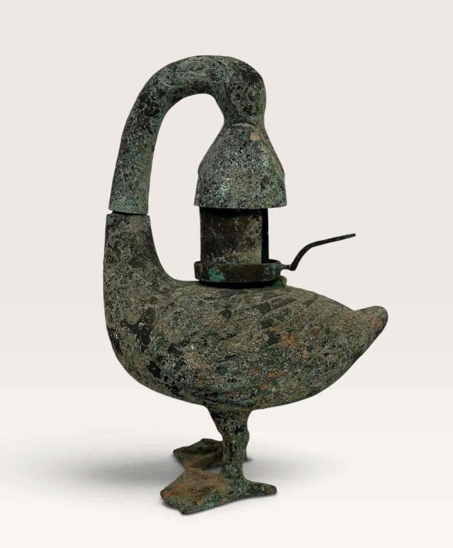 BRONZE ARCHAISTIC CHINESE GOOSE OIL LAMP: Archaistic bronze oil lamp modelled as a standing goose with arched neck and hinged cover, allover green patina Approximate Dimensions: 23" H x 16" W x 8" D Artist or Maker: Unknown Proven