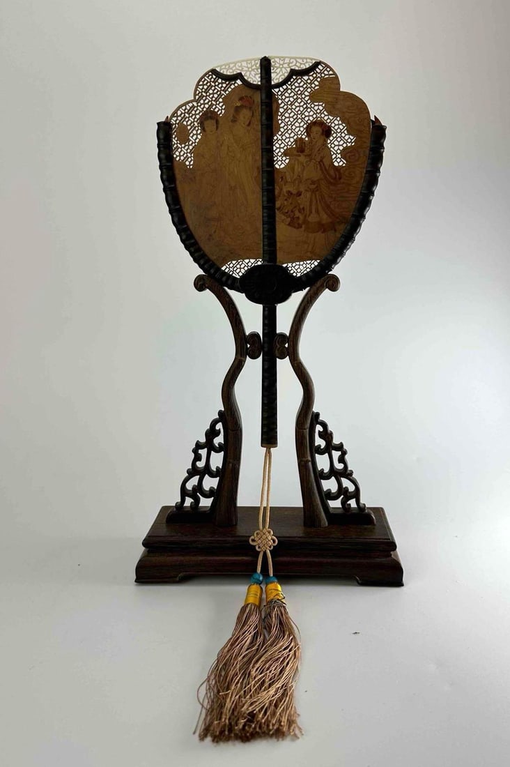 TRADITIONAL CHINESE CARVED WOOD OPENWORK PALACE FAN IN PRESENTATION BOX: Chinese fixed palace fan with pierced and carved wood frame and tassel, fitted in a silk covered presentation box with a display stand Approximate Dimensions Box: 2.5" H x 12.5" W x 8" D A