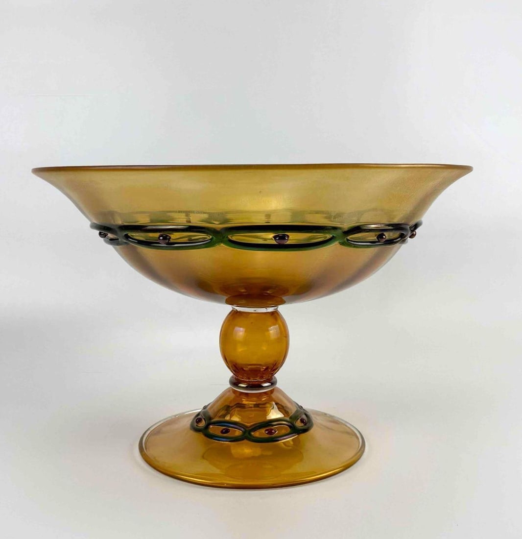 CENDESE MURANO IRIDESCENT AMBER GLASS FOOTED CENTERBOWL WITH APPLIED GREEN CHAIN: Large footed glass centerbowl of shallow flaring form, amber body with an allover golden iridescent surface, SIGNED. Approximate Dimensions: 10" H x 14.5" Dia. Artist or Maker: Cenedese Proven