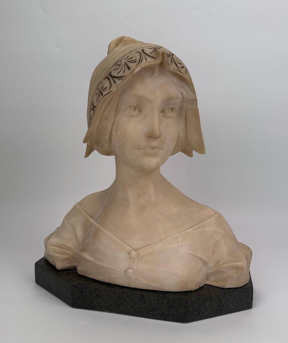 A. GENNAI SIGNED CARVED ALABASTER BUST OF A YOUNG WOMAN IN A HOOD: Carved alabaster bust of a young woman, her head turned and draped in a hood banded with a carved anthemion frieze, loose drapery across the shoulders, signed A. Gennai. Approximate Dimensions: 14"