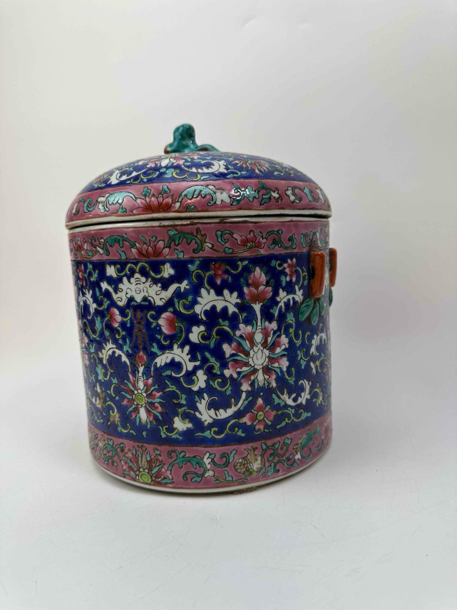 ANTIQUE CHINESE FAMILLE ROSE PORCELAIN TEA CADDY: Chinese famille rose porcelain covered jar with lotus scroll on a blue ground and foo lion finial. Approx. Dimensions: 9" x 9" x 10" Artist or Maker: Unknown Provenance: From a New York Collector Note
