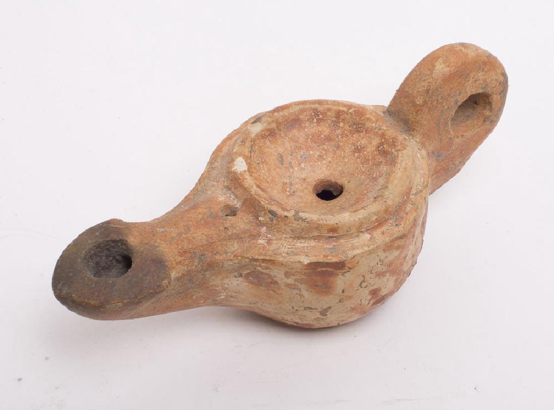 Islamic Period Terracotta Oil lamp Semi volute nozzle,: Islamic Period Terracotta Oil lamp. Size 4 5/8 inches length. 11.5 cm Semi volute nozzle, wide body and large handle. ex: Montana Collection Ex: Pearlman. Ex Maryland collection.