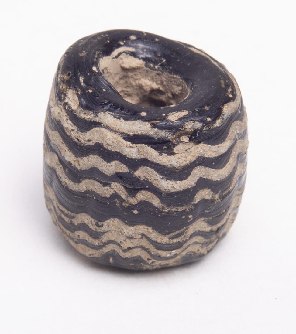 Ancient Phoenician Core-formed Glass Bead c.5th ce BC: Ancient Phoenician Core-formed Glass Bead c.5th century BC. size 19-19 mm. Fine Phoenician Core-formed black glass bead with applied spiral tail. Condition: perfect. Provenance: Ex, Robert Thompson, E