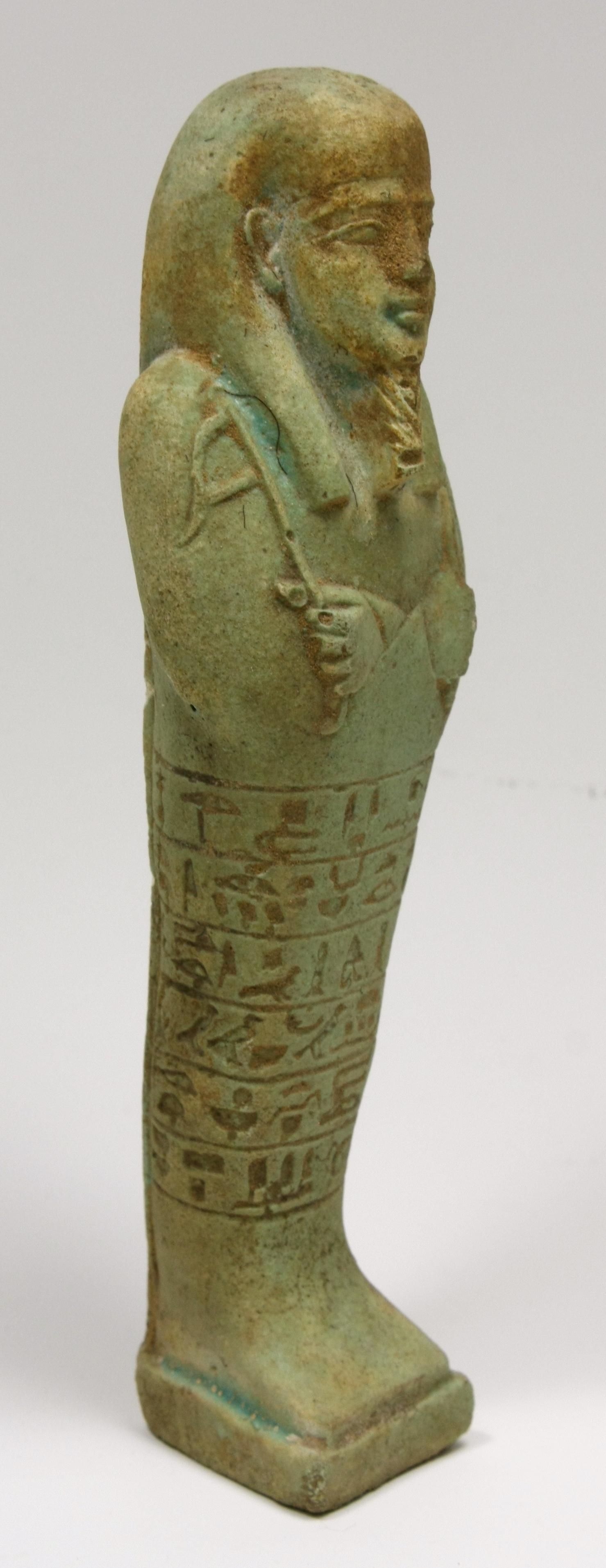 Ancient Egyptian Blue Faience Ushabti Figure c.700 BC.: Ancient Egyptian Blue Faience Ushabti Figure c.700 BC. Size 6 7/8 inches high.(17.46 cm) A large green glazed faience ushabti figure, wearing the royal wig and beard, holding implements and seed sack 