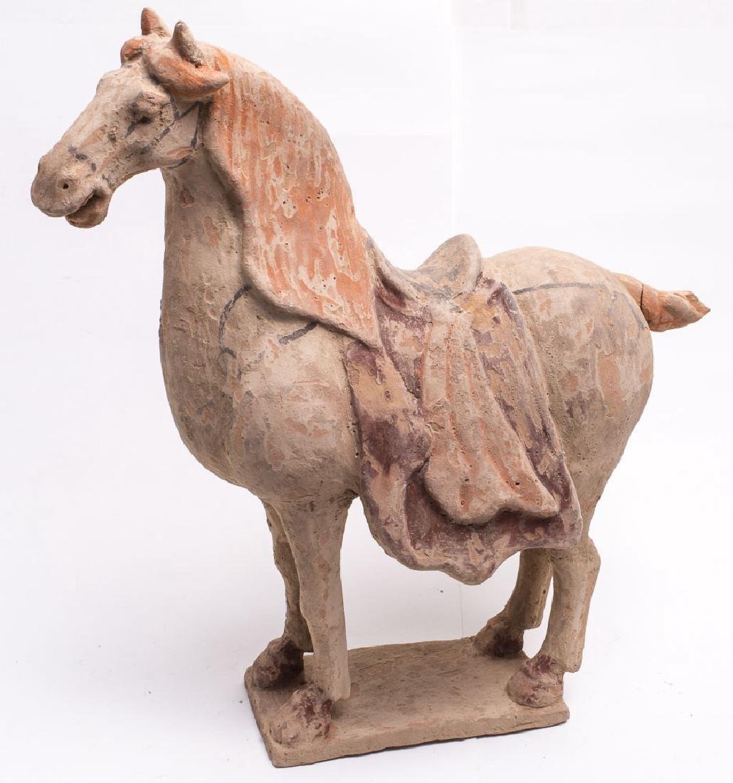 A Chinese Pottery Model of a Horse, Tang Dynasty Style.: A Chinese Pottery Model of a Horse, Tang Dynasty Style. Size 14 3/8 inches high x 14 inches wide. Condition:Tail repaired and chipped. The buff coloured horse modelled standing, its head turned slight