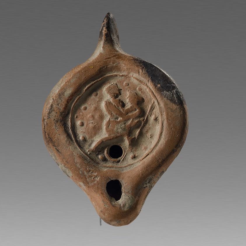 Ancient Roman North African Erotic Terracotta Oil Lamp: Ancient Roman North African Erotic Terracotta Oil Lamp c.4th century AD. Size 4 1/4 inches length. Redware terracotta oil lamp decorated with couple making love setaed pos on discus with raised dots a
