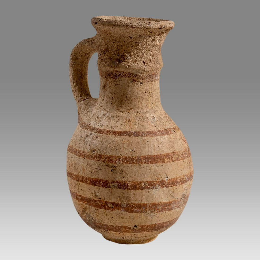 Early Phoenician or Holland Pottery Beer Bottle 2nd Millennium BC.: Early Phoenician or Holland Pottery Beer Bottle 2nd Millennium BC. Size 5 3/8 inches high. Buff clay bottle with tapered cylindrical neck, rounded base and loop handle. Decorated in red slip with band