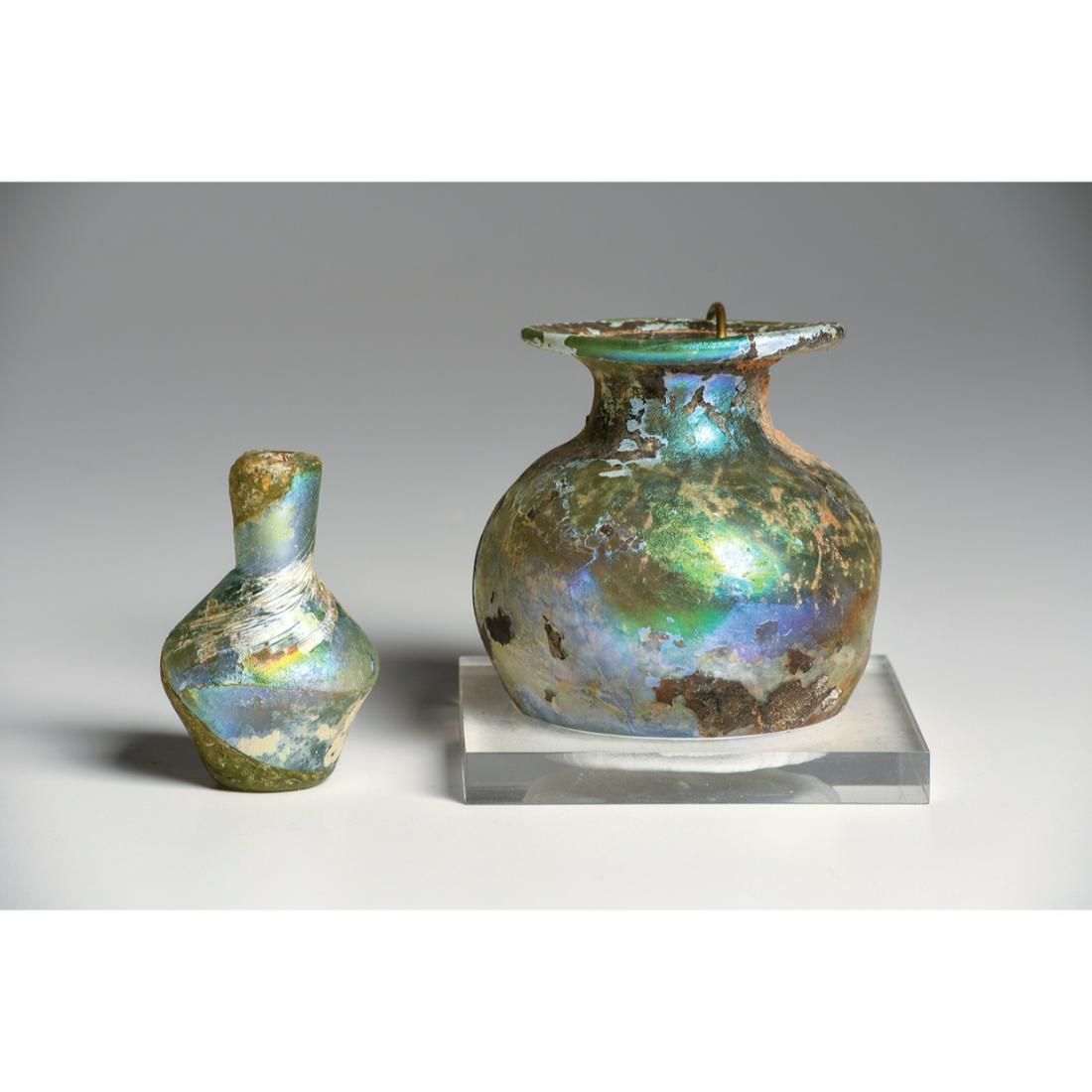 Lot of 2 Ancient Roman Iridescent Glass Jar & Bottle Ca. 1st - 2nd century A.D.: Lot of 2 Ancient Roman Iridescent Glass Jar & Bottle Ca. 1st - 2nd century A.D. Size 3 1/4 - 2 1/2 inches high. Including a yellow-green color glass bottle having a swirl pattern molded body, short ne