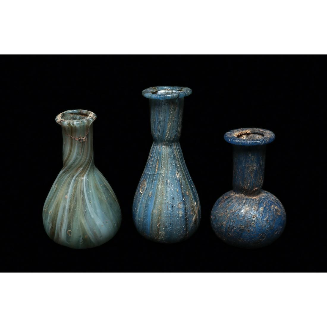 Lot of 3 Ancient Roman Blue Marbled Glass Bottles Ca. 1st - 3rd century A.D.: Lot of 3 Ancient Roman Blue Marbled Glass Bottles Ca. 1st - 3rd century A.D. Size 2 3/8 - 3 1/8 inches high. Three different blown glass examples, in various shades of blue with yellow, amber and whit