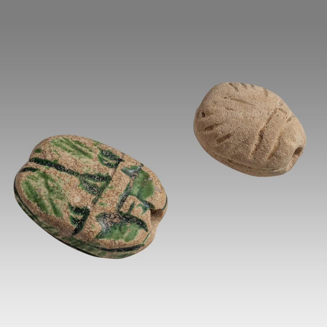 Lot of 2 Ancient Egyptian scarabs c.1100-30 BC.: Lot of 2 Ancient Egyptian scarabs c.1100-30 BC. Size 17-12 mm. Two scarabs. The glazed example exhibits traces of three glyphs or letters and may be Phoenecian. The other is a simple clay formed scara