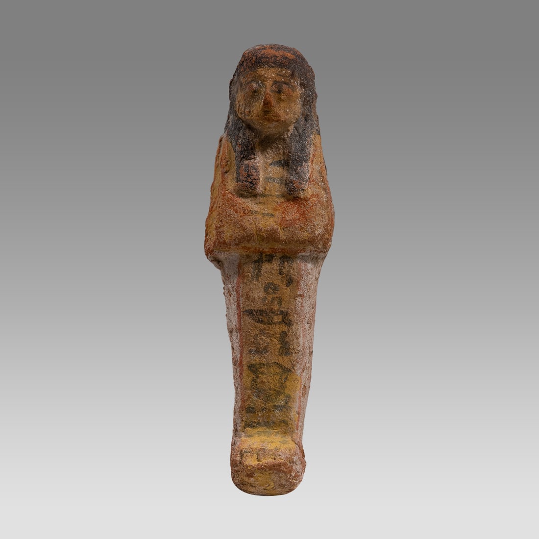 Ancient Egyptian Terracotta Ushabti Ca. late 19th Dynasty, ca. 1295 - 1186 B.C.: Ancient Egyptian Terracotta Ushabti Ca. late 19th Dynasty, ca. 1295 - 1186 B.C. Size 6 1/4 inches high. Molded terracotta ushabti, wearing a black painted royal wig, holding red painted royal implemen