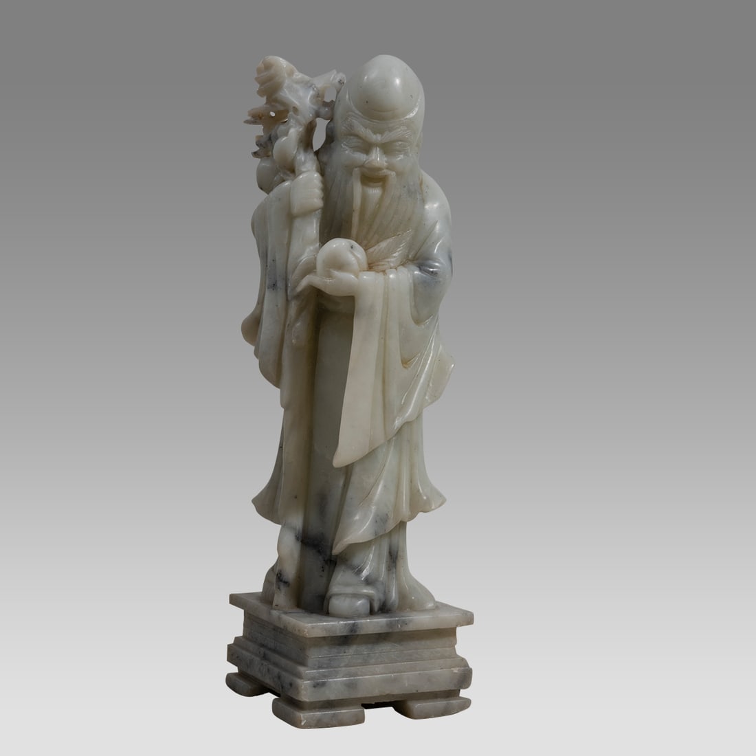 Chinese Marble figure of a Man.: Chinese Marble figure of a Man. Size 12 1/2 inches high. Carved marble figure of an old bearded man standing on a square base holding object in his left handt and a plant in his right hand. From the e