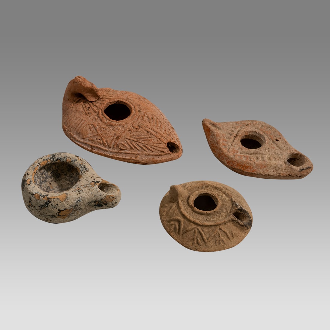 Lot of 4 Ancient Holy Land Terracotta Oil Lamps c.1st century BC-3rd century AD.: Lot of 4 Ancient Holy Land Terracotta Oil Lamps c.1st century BC-3rd century AD. Size 2 5/8 - 4 5/8 inches length. Lovey collection of mixed tyoes and era Holy land terracotta oil lamps. Provenance: E