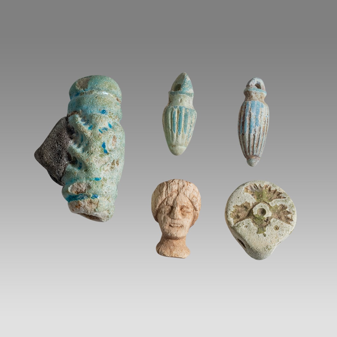 Lot of 5 Ancient Egyptian Faience and Bone Amulets Roman Period c.1st-2nd century AD.: Lot of 5 Ancient Egyptian Faience and Bone Amulets Roman Period c.1st-2nd century AD. Size 20-38 mm. A collection of 4 faience bead amulets together with a small bone head of a woman. Provenance:, Ex