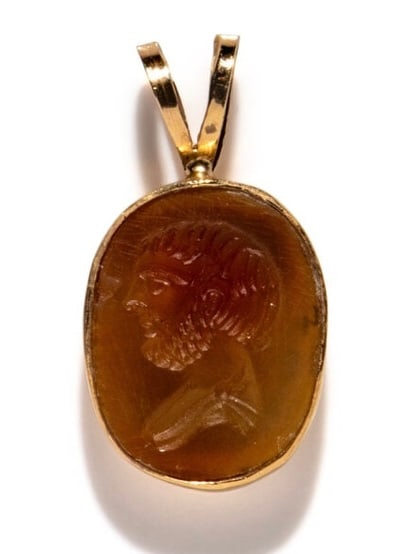 A Neoclassical Gold and Carnelian Pendant with a Male Portrait Head.: A Neoclassical Gold and Carnelian Pendant with a Male Portrait Head Late 18th–Early 19th Century Intaglio size: 27 x 15 mm Total weight: 4.06 g 14 karat goldA finely carved carnelian intaglio depict