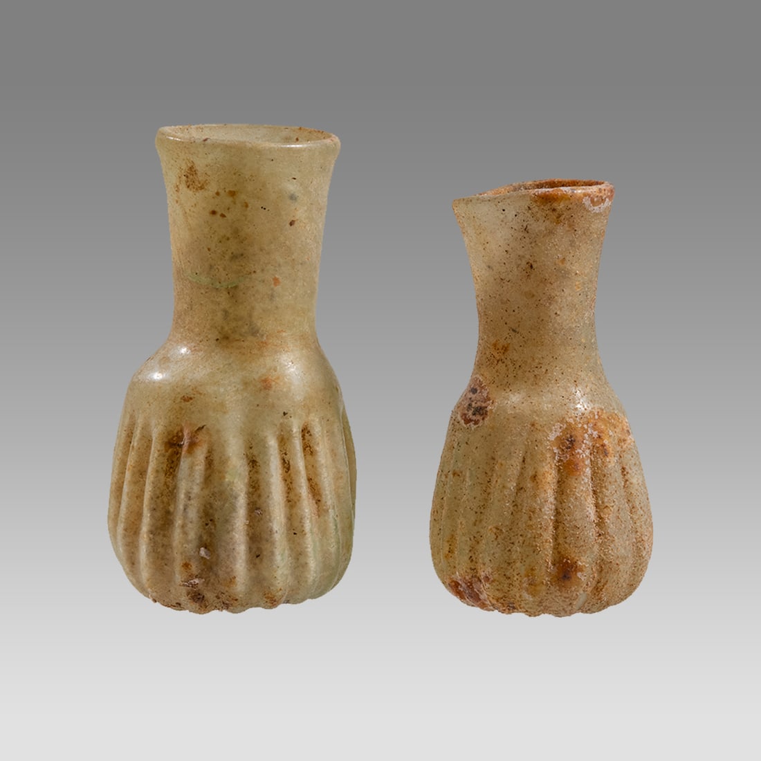 Lot of 2 Ancient Roman Glass Bottles c.2nd-4th century AD.: Lot of 2 Ancient Roman Glass Bottles c.2nd-4th century AD. Size 2 1/2 - 2 7/8 inches high. A matching pair of Roman ribbed glass bottles with wide neck and rim. Provenance: Ex Private New York city co