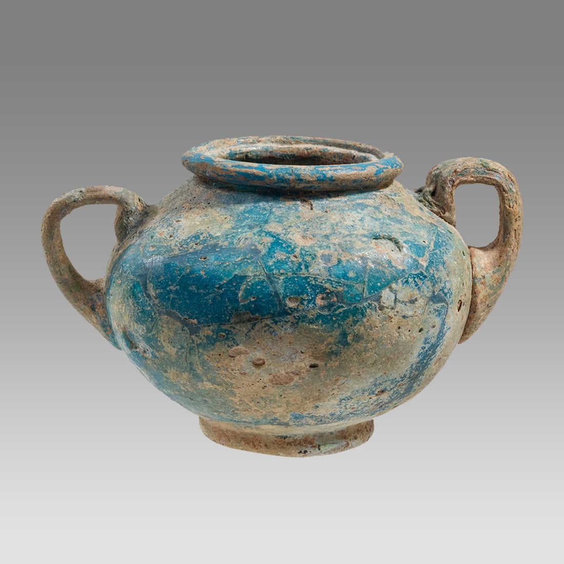 Ancient Sidonian Opaque Blue Glass Vessel Circa 1st Century A.D.: Ancient Sidonian Opaque Blue Glass Vessel Circa 1st Century A.D. Size 2 inches high, 3 1/4 inches across handle span. Rare blue opaque footed glass vessel with twin handles at shoulder. Provenance: Ex