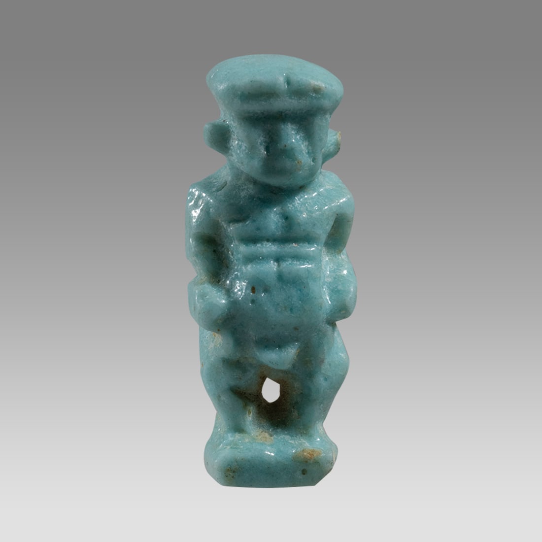 Ancient Egyptian Faience Amulet Of Dwarf Pataikos LATE PERIOD CIRCA 664-332 B.C.: Ancient Egyptian Faience Amulet Of Dwarf Pataikos LATE PERIOD CIRCA 664-332 B.C. Size 1 inch high. Light blue glazed faience Amulet of Dwarf Pataikos, Suspension hole at back. Provenance: Private coll