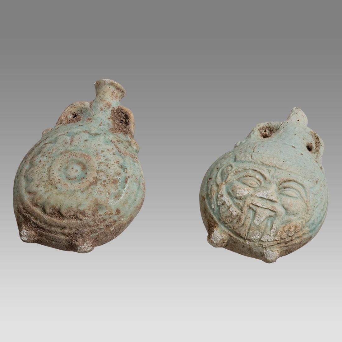 Lot of 2 Ancient Egyptian Faience Flasks c.664-332 BC.: Lot of 2 Ancient Egyptian Faience Flasks c.664-332 BC. Size 2 3/8 - 2 1/2 inches high. Rare ancient Egyptian blue faience small flasks one with face of Bes, the other with floral design on both sides.