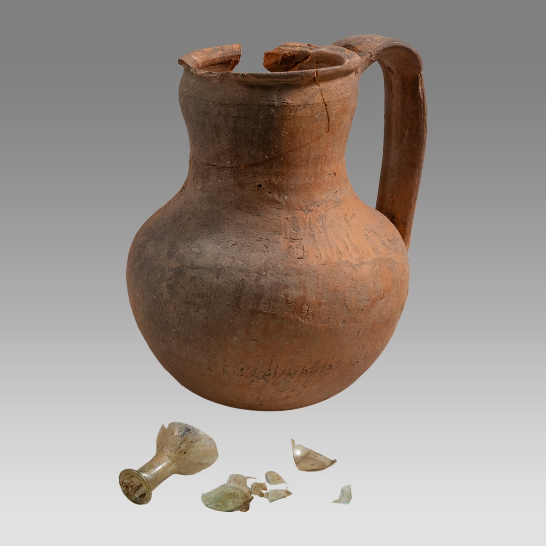 Lot of 2 Ancient Roman Terracotta Jug, Glass Bottle c.1st-2nd century AD.: Lot of 2 Ancient Roman Terracotta Jug, Glass Bottle c.1st-2nd century AD. Size 6 1/4 inches high, Glass 1 1/2 inch high. A red terracotta jug with strap handle together with a small glass bottle. Both