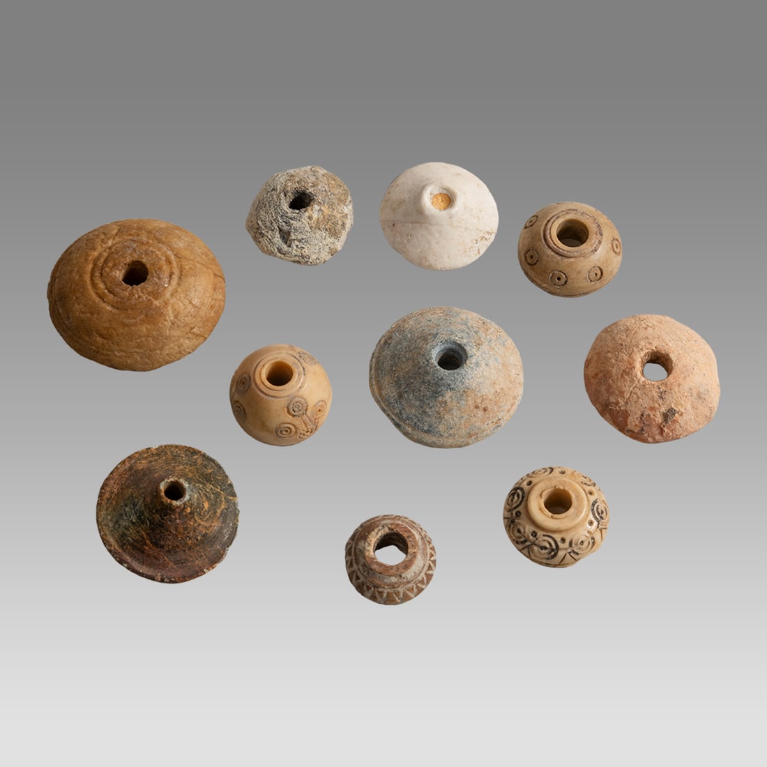 Lot of 10 Roman Bone Spindle Whorls c.2nd-4th century AD.: Lot of 10 Roman Bone Spindle Whorls c.2nd-4th century AD. Size 15-30 mm. Fine carved bone spindle whorls some with decoration. hole through the center. Ex Florida collection.