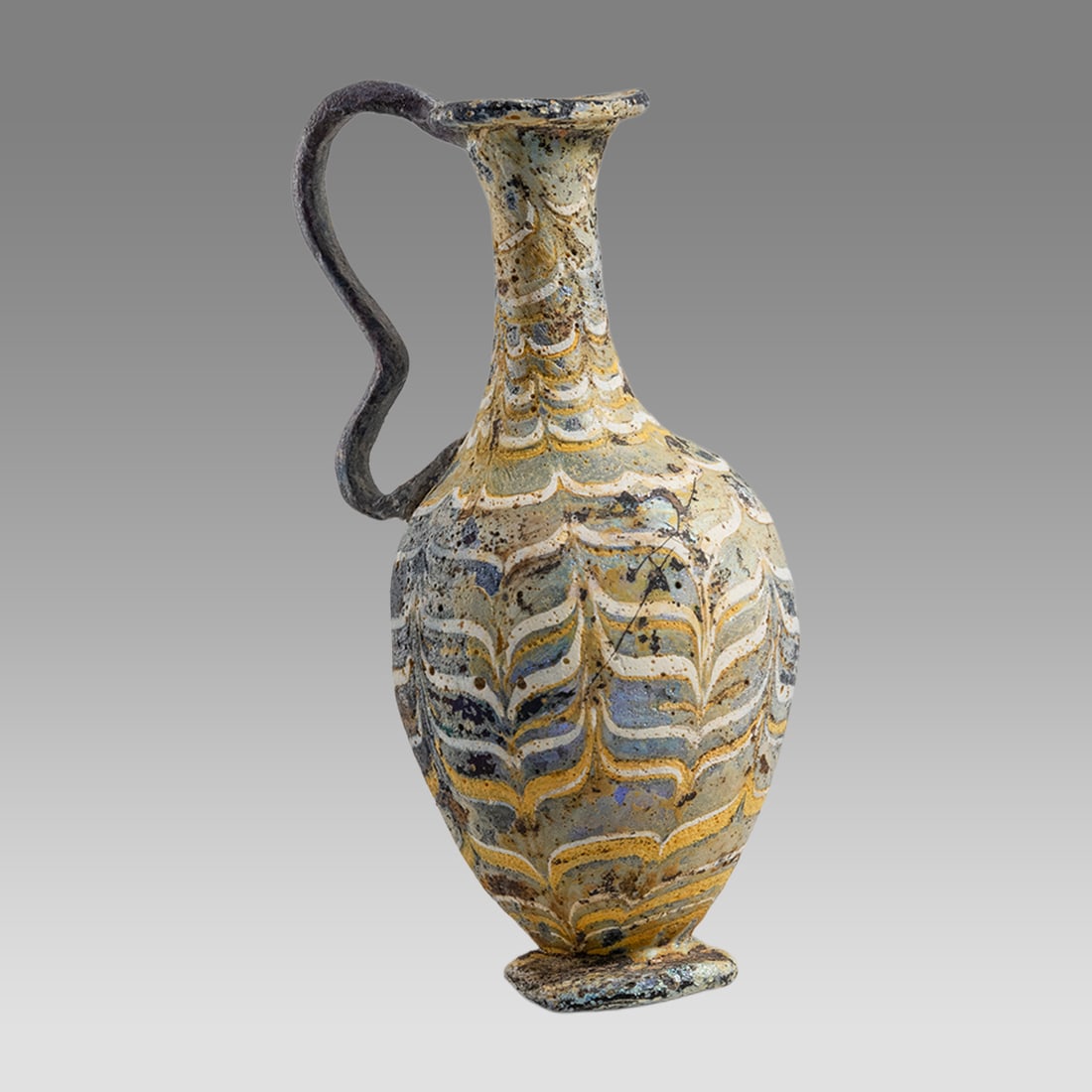 Ancient Greek Core-formed Glass Oinochoe Ca. 6th - 5th century B.C.: Ancient Greek Core-formed Glass Oinochoe Ca. 6th - 5th century B.C. Size 4 3/8 inches high. 2 1/4 inches width. Core formed glass oinochoe having a round lip, applied ornate handle and disc foot. Deco