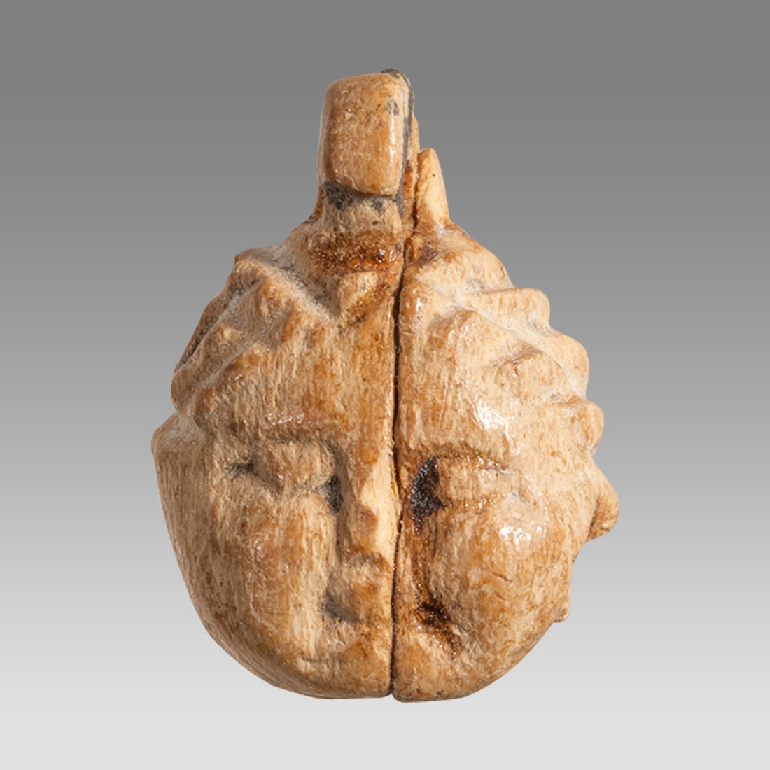 Ancient Roman Bone Amulet c.2nd century AD.: Ancient Roman Bone Amulet c.2nd century AD. Size 14 x 11 mm. Carved bone amulet depicting Child face with suspension loop. Provenance: Private London collection; previously acquired from a Belgian col