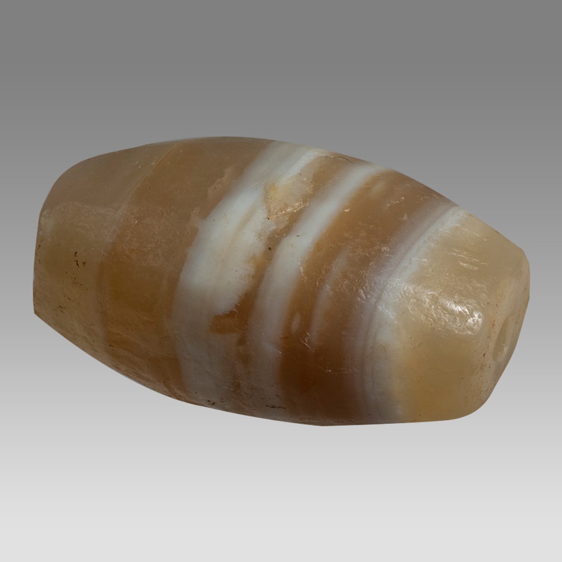 Ancient Mesopotamian Banded Agate Bead c.6th century BC.: Ancient Mesopotamian Banded Agate Bead c.6th century BC. Size 29 x 17 mm. Carved banded agate large bead with suspension hole in the center. Ex Altmar, NY private collection.