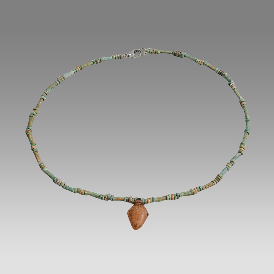 Ancient Egyptian Faience Mummy Bead Necklace with Agate Heart Amulet: An ancient Egyptian faience mummy bead necklace, Late Period, circa 300-50 BC, 17.75 inches in length, strung with an agate heart amulet. The heart amulet (Ib) held profound significance in ancient Eg