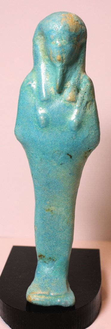 An Egyptian bright blue faience ushabti, Late Period: An Egyptian bright blue faience ushabti, Late Period, 30th Dynasty, c. 380 - 343 BC, mummiform, wearing tripartite wig, arms folded over chest. Great blue color. old repair at the bottom feet from the